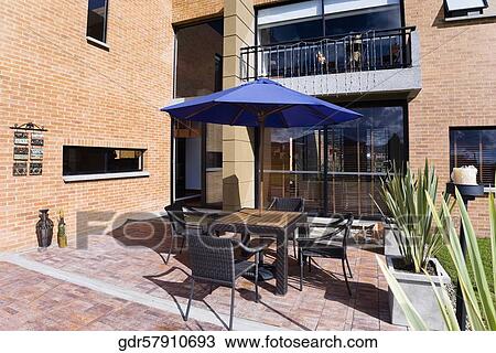 Chairs with a patio umbrella in the courtyard of a house View Large Photo Image Stock Image - Chairs with a patio umbrella in the courtyard of a house. Fotosearch