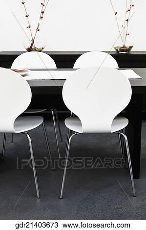 Stock Image - Chairs with a table in a dining room. Fotosearch