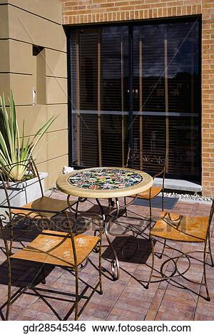 Stock Photograph - Chairs with a table in the courtyard of a house. Fotosearch