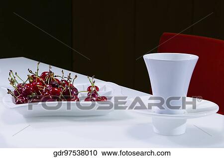 Stock Image - Cherries with a tea cup on a table. Fotosearch