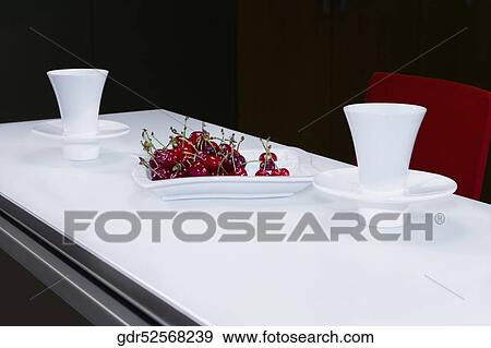 Stock Photo - Cherries with tea cups on a table. Fotosearch