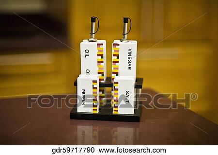 Stock Image - Close-up of salt shaker and pepper shaker with bottles. Fotosearch