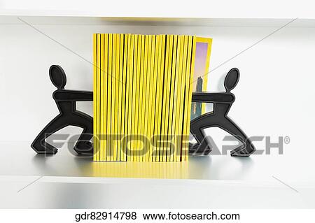 Close-up of two figurines pushing books View Large Photo Image Stock Photo - Close-up of two figurines pushing books. Fotosearch