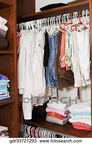 Clothing hanging in a closet View Large Photo Image Stock Image - Clothing hanging in a closet. Fotosearch