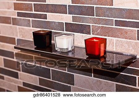 Stock Photo - Colorful candles on a shelf in the bathroom. Fotosearch