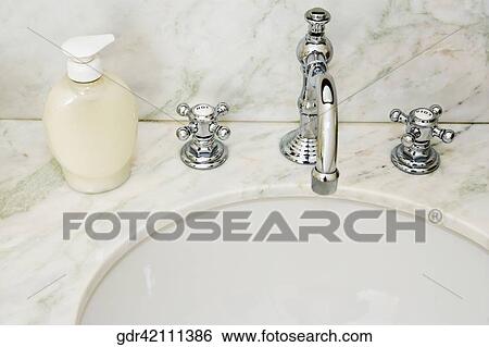 Faucet with soap dispenser near a wash bowl View Large Photo Image Stock Photograph - Faucet with soap dispenser near a wash bowl. Fotosearch