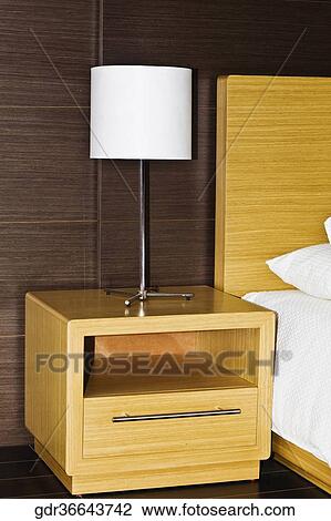 Lamp on a night table beside a bed View Large Photo Image Stock Image - Lamp on a night table beside a bed. Fotosearch