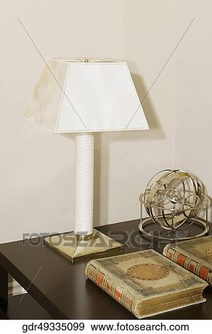 Lamp with books and a show piece on a table View Large Photo Image Stock Photo - Lamp with books and a show piece on a table. Fotosearch