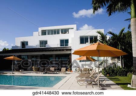 Stock Image - Lounge chairs and patio umbrellas at the poolside. Fotosearch