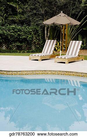 Stock Image - Lounge chairs at the poolside. Fotosearch