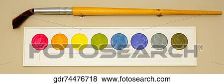 Stock Photo - Palette of watercolor paints with a paintbrush mounted on a wall. Fotosearch