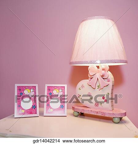 Picture - Picture frames and a lamp on a night table. Fotosearch