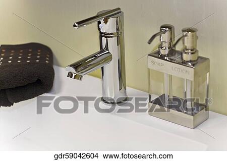 Soap dispenser near a faucet on a wash bowl View Large Photo Image Picture - Soap dispenser near a faucet on a wash bowl. Fotosearch