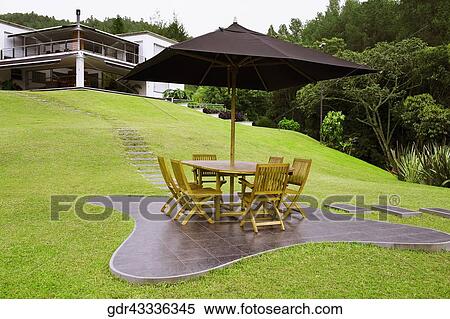Table and chairs under a patio umbrella in a lawn View Large Photo Image Stock Photography - Table and chairs under a patio umbrella in a lawn. Fotosearch