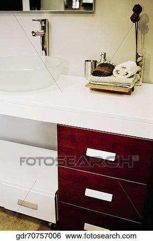 Toiletries near a wash bowl on a cabinet View Large Photo Image Stock Photograph - Toiletries near a wash bowl on a cabinet. Fotosearch