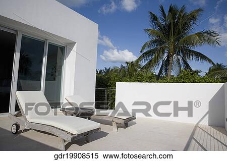 Two reclining chairs in a balcony View Large Photo Image Stock Photography - Two reclining chairs in a balcony. Fotosearch