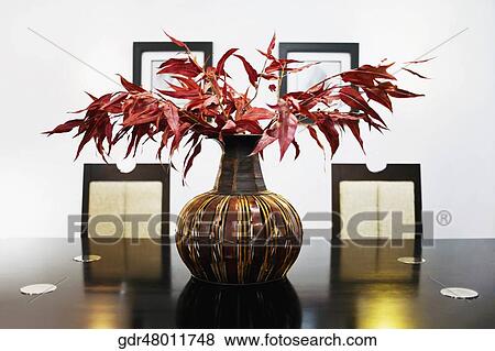 Vase with artificial leaves on a dining table View Large Photo Image Stock Photo - Vase with artificial leaves on a dining table. Fotosearch
