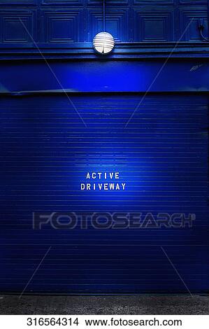 Picture - Active driveway sign on a blue painted wall. Fotosearch