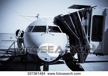 Picture - Airplane attached to passenger boarding bridge at an airport. Fotosearch