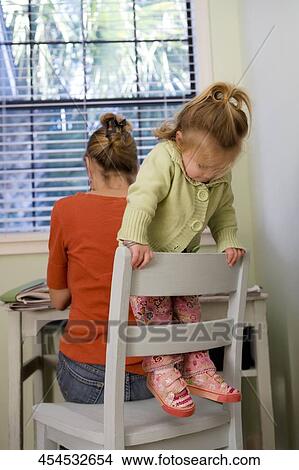 Picture - Baby girl playing on a chair with her mother sitting behind her. Fotosearch