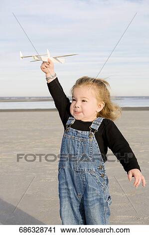 Baby girl playing with a model airplane on the beach View Large Photo Image Stock Image - Baby girl playing with a model airplane on the beach. Fotosearch