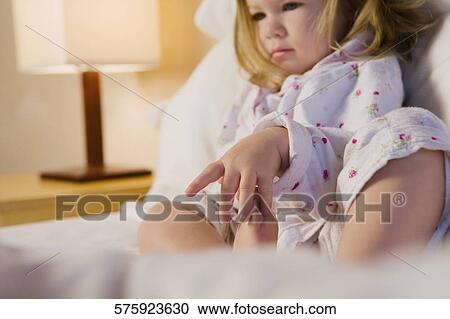 Stock Image - Baby girl reclining on the bed and thinking. Fotosearch