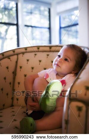 Stock Image - Baby girl sitting in an armchair. Fotosearch