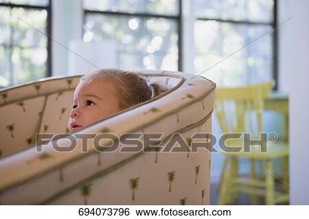 Stock Photograph - Baby girl sitting in an armchair. Fotosearch
