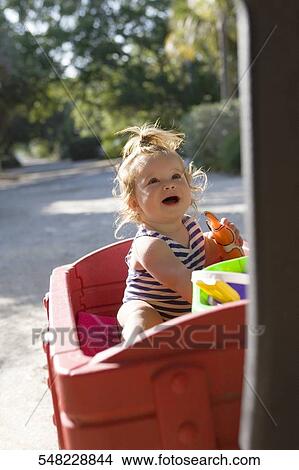 Baby girl sitting on a toy cart View Large Photo Image Picture - Baby girl sitting on a toy cart. Fotosearch