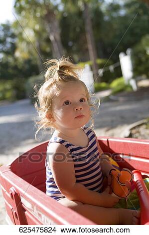 Baby girl sitting on a toy cart View Large Photo Image Picture - Baby girl sitting on a toy cart. Fotosearch
