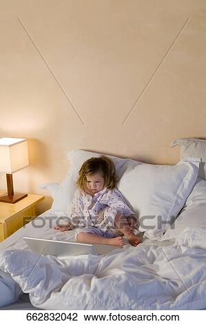 Baby girl sitting on the bed and looking at a laptop View Large Photo Image Stock Image - Baby girl sitting on the bed and looking at a laptop. Fotosearch