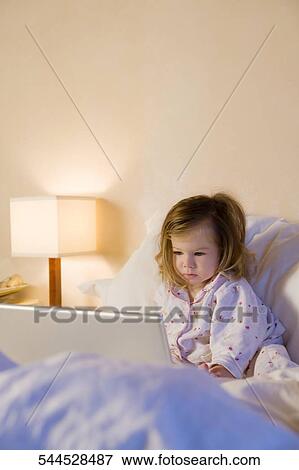 Baby girl sitting on the bed and using a laptop View Large Photo Image Stock Photo - Baby girl sitting on the bed and using a laptop. Fotosearch
