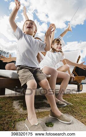 Boy and a girl playing with their parents on a lounge chair View Large Photo Image Stock Photography - Boy and a girl playing with their parents on a lounge chair. Fotosearch