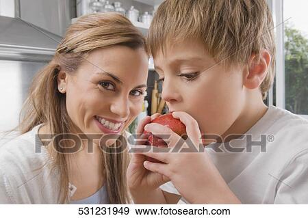 Boy eating an apple and his mother smiling View Large Photo Image Stock Photo - Boy eating an apple and his mother smiling. Fotosearch