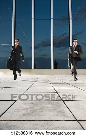 Businessman and a businesswoman running with a briefcase View Large Photo Image Stock Photograph - Businessman and a businesswoman running with a briefcase. Fotosearch