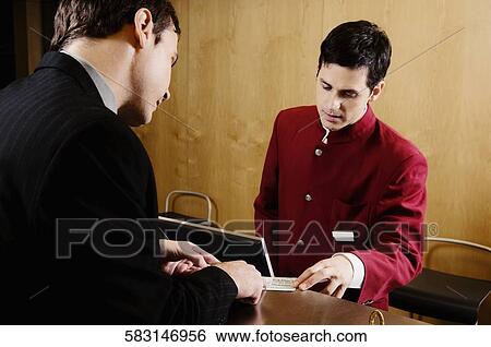 Businessman checking a card at hotel reception View Large Photo Image Stock Photograph - Businessman checking a card at hotel reception. Fotosearch