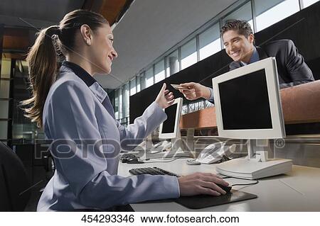 Stock Photograph - Businessman giving a credit card to a businesswoman. Fotosearch