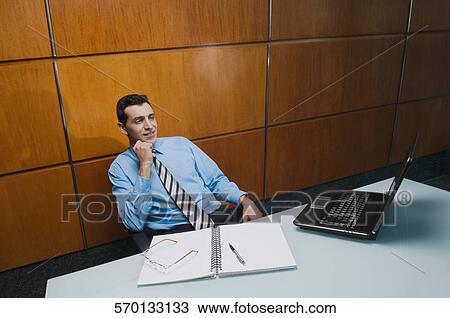 Stock Image - Businessman looking at a laptop in an office. Fotosearch