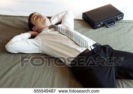 Businessman lying on the bed and napping View Large Photo Image Stock Photo - Businessman lying on the bed and napping. Fotosearch