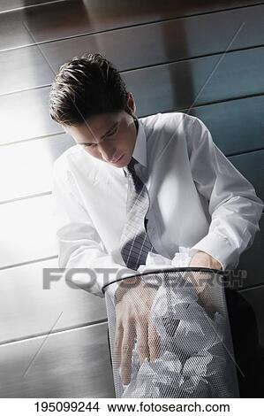 Businessman searching in a wastepaper basket View Large Photo Image Picture - Businessman searching in a wastepaper basket. Fotosearch
