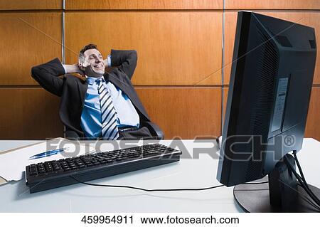 Stock Image - Businessman sitting in an office chair and day dreaming. Fotosearch