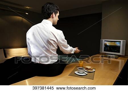 Businessman sitting on a desk and watching television View Large Photo Image Stock Photography - Businessman sitting on a desk and watching television. Fotosearch