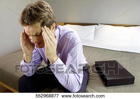 Businessman sitting on the bed and suffering from a headache View Large Photo Image Stock Photo - Businessman sitting on the bed and suffering from a headache. Fotosearch