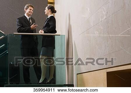 Businessman talking to a businesswoman and smiling View Large Photo Image Stock Image - Businessman talking to a businesswoman and smiling. Fotosearch