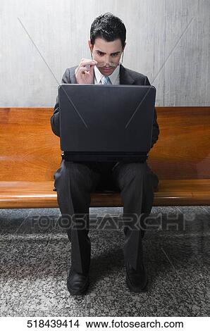 Businessman using a laptop on a bench View Large Photo Image Picture - Businessman using a laptop on a bench. Fotosearch