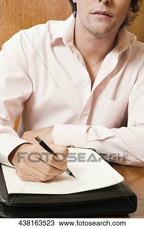 Businessman writing on a sheet of paper with a pen View Large Photo Image Stock Image - Businessman writing on a sheet of paper with a pen. Fotosearch