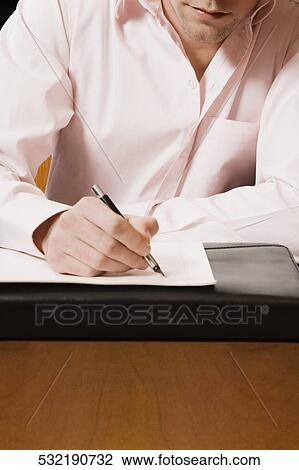 Businessman writing on a sheet of paper with a pen View Large Photo Image Stock Image - Businessman writing on a sheet of paper with a pen. Fotosearch