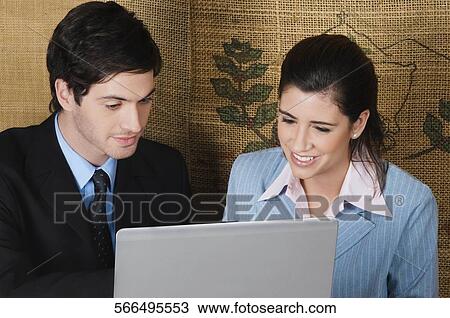 Businesswoman and a businessman using a laptop in a cafe View Large Photo Image Stock Image - Businesswoman and a businessman using a laptop in a cafe. Fotosearch