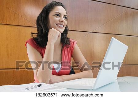 Businesswoman dreaming in front of a laptop smiling View Large Photo Image Stock Image - Businesswoman dreaming in front of a laptop smiling. Fotosearch