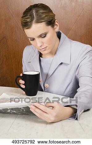 Businesswoman reading a newspaper and holding a coffee cup View Large Photo Image Stock Image - Businesswoman reading a newspaper and holding a coffee cup. Fotosearch